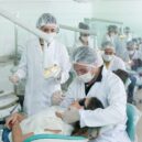 Dental interns in protective gear treating a patient, showcasing real-world clinical experience in an international internship.