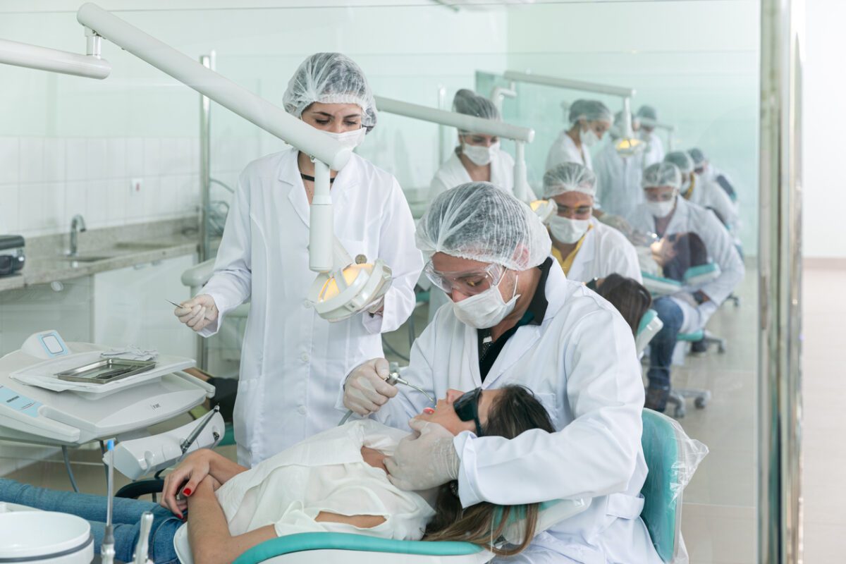 Dental interns in protective gear treating a patient, showcasing real-world clinical experience in an international internship.